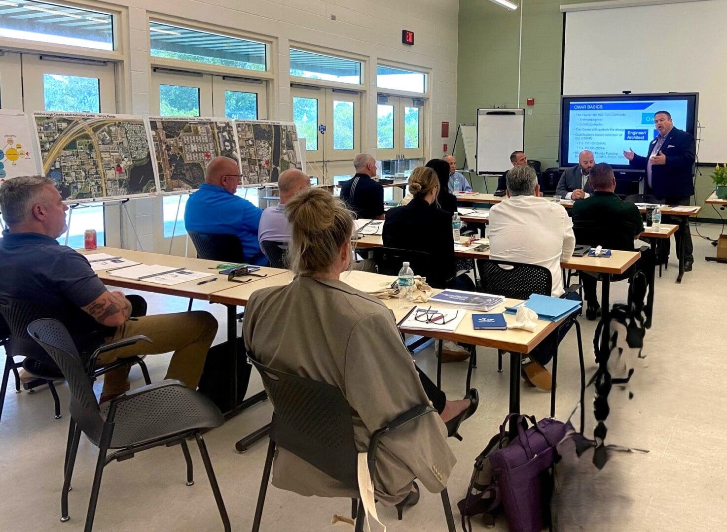 Students attend a classroom lecture with a presentation screen at the front.