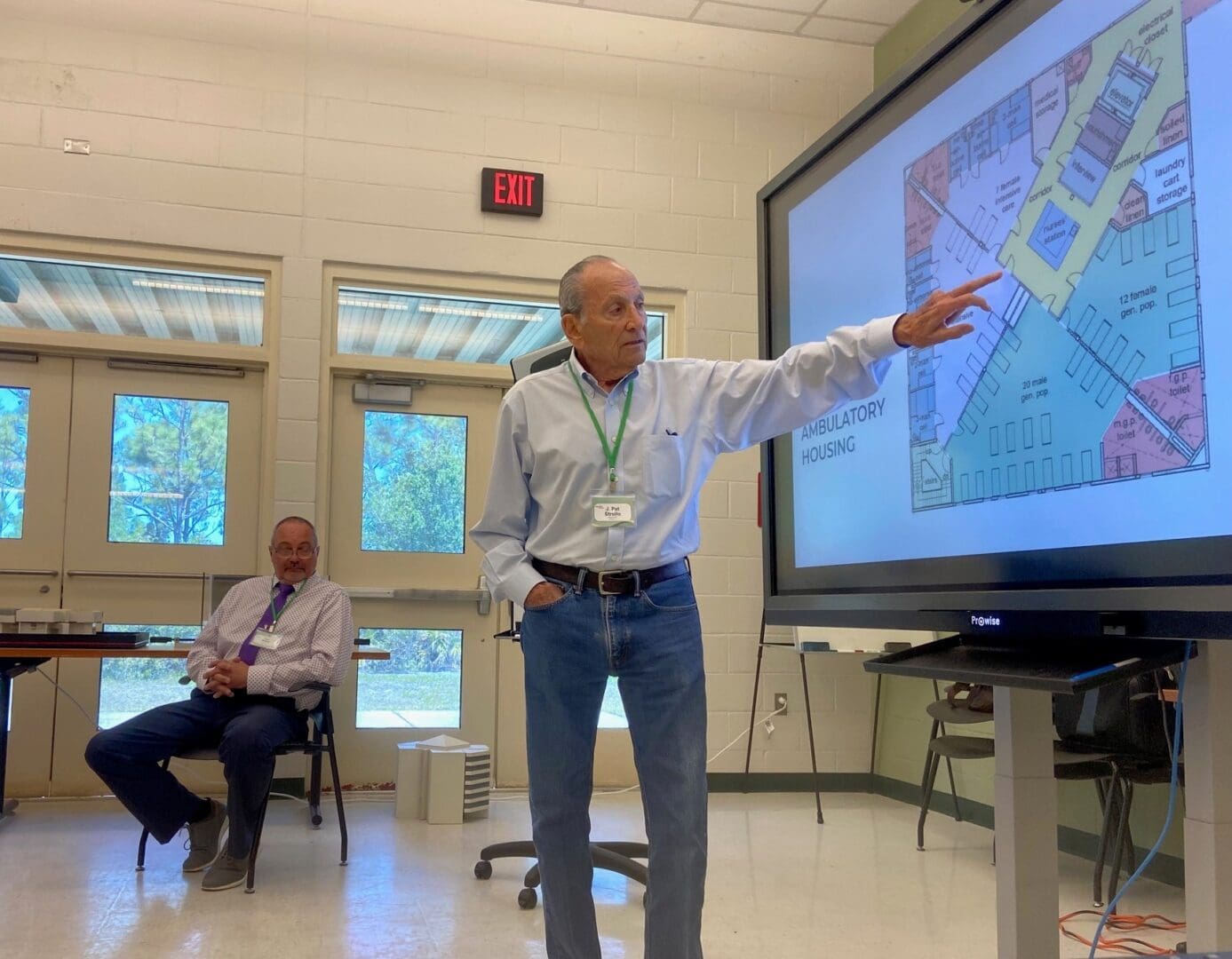 Man presenting information on a large screen in a classroom.